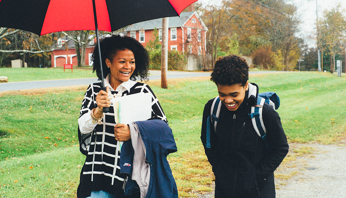 Eden-Reneé Hayes walking with student under umbrella