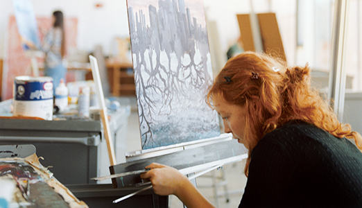 A femaale student works during her painting studio.
