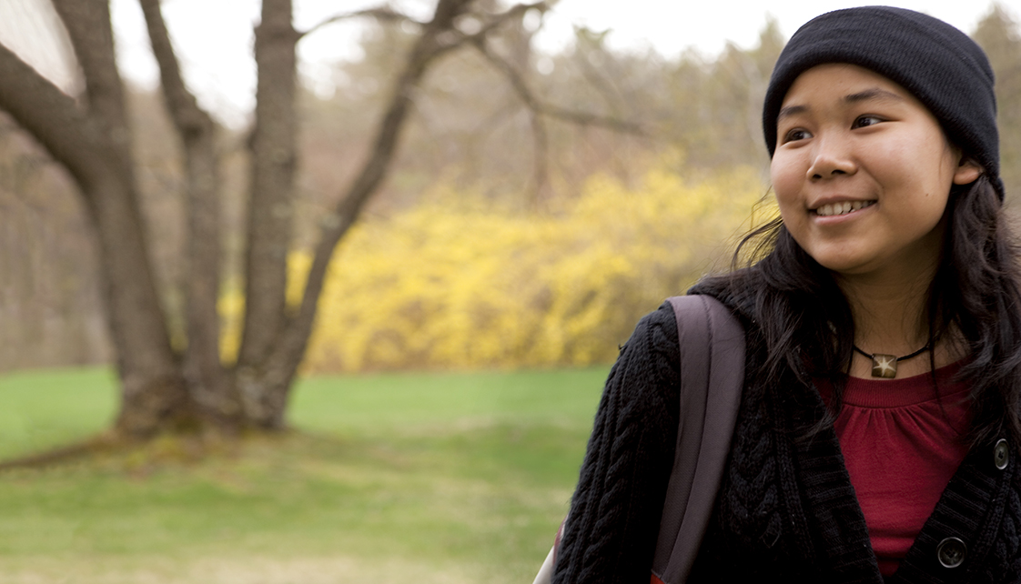 Female student in knit hat smiling on campus.